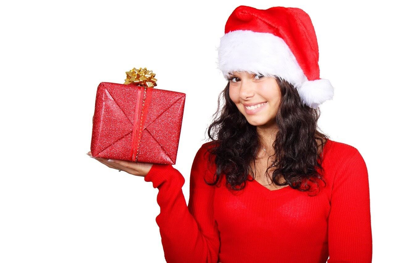 smiling girl in santa hat holding present