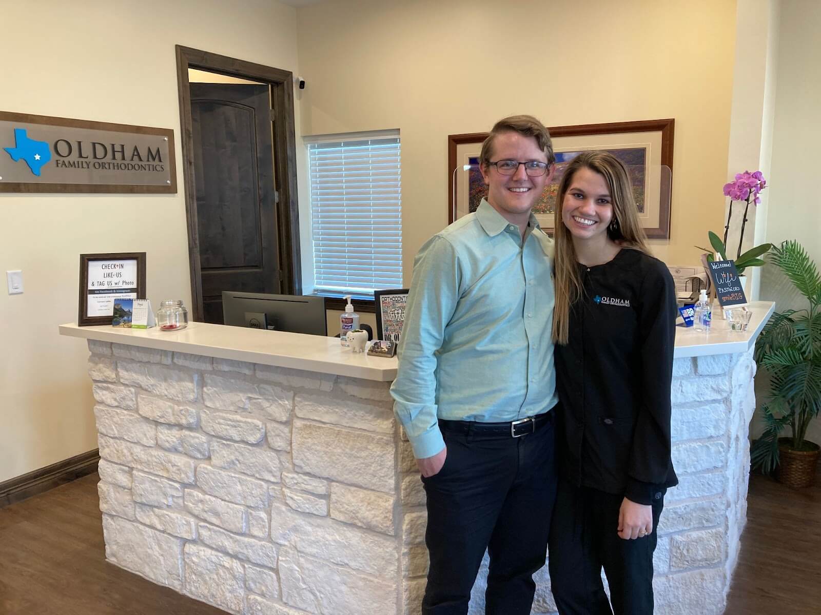 Two people posing in front of the front desk